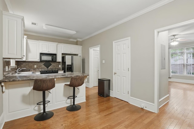 7106 Ohio St Unit 6, Little Rock, AR 72207 - kitchen with black appliances, a peninsula, tasteful backsplash, light wood-type flooring, and crown molding