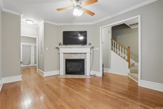 7106 Ohio St Unit 6, Little Rock, AR 72207 - unfurnished living room featuring ornamental molding, light wood-style flooring, stairs, ceiling fan, and a tiled fireplace