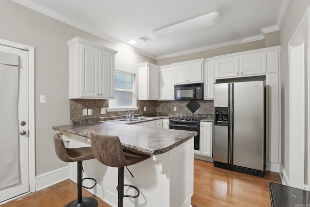 7106 Ohio St Unit 6, Little Rock, AR 72207 - kitchen with black appliances, a peninsula, a sink, white cabinets, and decorative backsplash