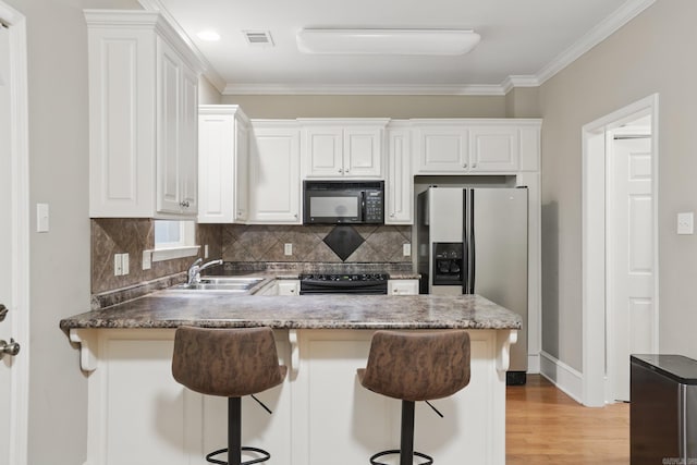 7106 Ohio St Unit 6, Little Rock, AR 72207 - kitchen featuring black appliances, a sink, a peninsula, decorative backsplash, and white cabinets