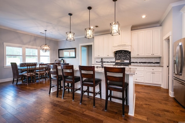 853 Rushing Rd, Little Rock, AR 72210 - kitchen with stainless steel appliances, ornamental molding, tasteful backsplash, white cabinets, and a center island with sink