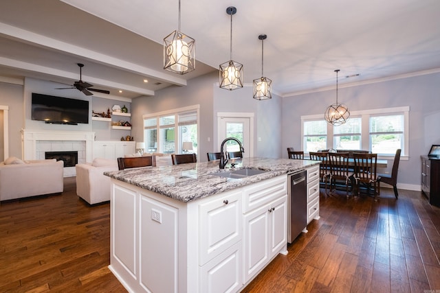 853 Rushing Rd, Little Rock, AR 72210 - kitchen featuring a sink, light stone counters, a tile fireplace, dark wood-style flooring, and a kitchen island with sink