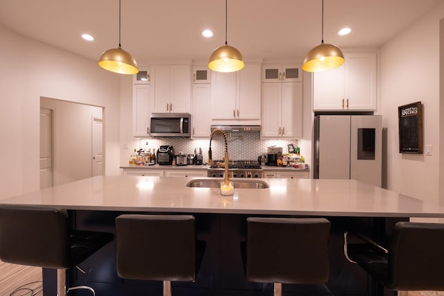 2103 Wolfe St, Little Rock, AR 72202 - kitchen featuring freestanding refrigerator, stainless steel microwave, under cabinet range hood, decorative backsplash, and light countertops