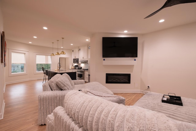 2103 Wolfe St, Little Rock, AR 72202 - living room with light wood-type flooring, a glass covered fireplace, recessed lighting, and baseboards