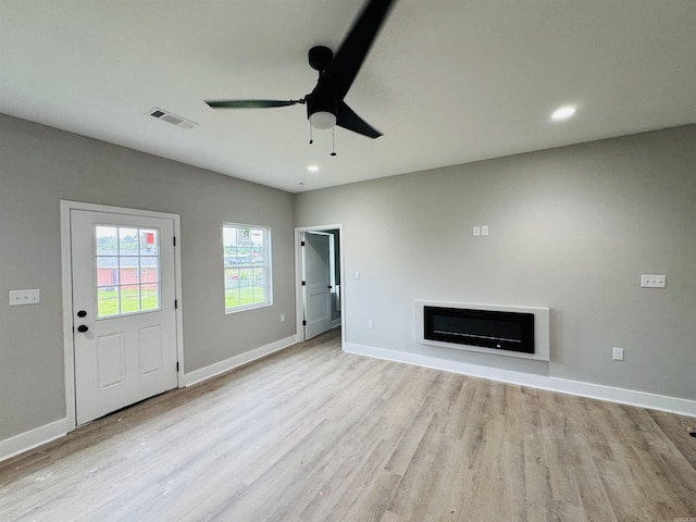 207 W Military Rd, North Little Rock, AR 72118 - unfurnished living room with wood finished floors, a glass covered fireplace, a ceiling fan, baseboards, and recessed lighting