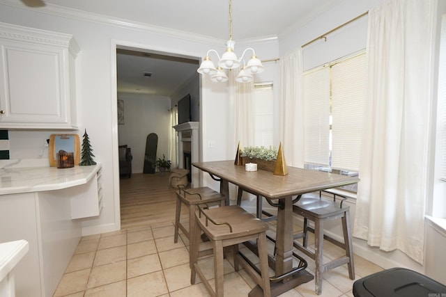 dining room with ornamental molding, a chandelier, a fireplace, and light tile patterned floors