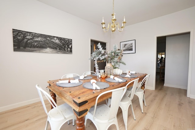 dining area with a chandelier, light wood finished floors, and baseboards