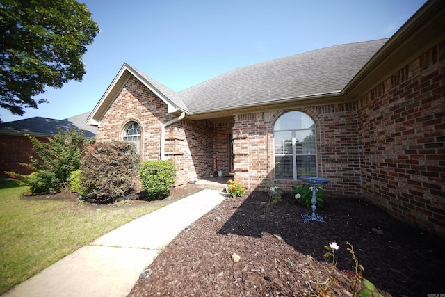 view of front of home featuring roof with shingles, brick siding, and a front yard