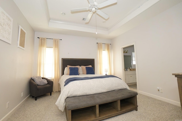 bedroom featuring a raised ceiling, light colored carpet, ornamental molding, baseboards, and connected bathroom