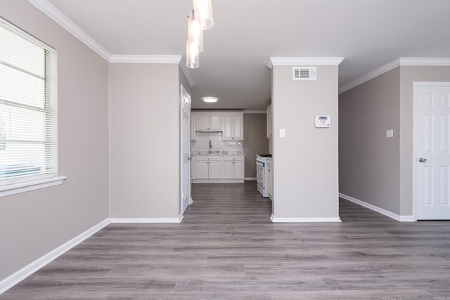 202 Gilbert Dr, Little Rock, AR 72205 - unfurnished living room featuring ornamental molding, baseboards, healthy amount of natural light, wood finished floors, and a sink
