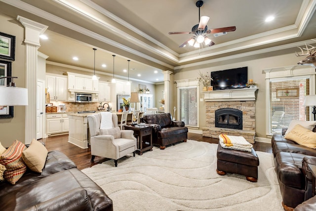 3891 Harrison Rd, Benton, AR 72019 - living room featuring decorative columns, dark wood-type flooring, a tray ceiling, ceiling fan, and crown molding