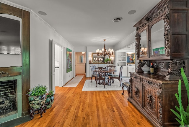 5412 S Grandview St, Little Rock, AR 72207 - dining space with a chandelier, light wood-style flooring, crown molding, and a fireplace