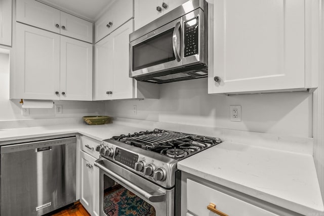 5412 S Grandview St, Little Rock, AR 72207 - kitchen featuring appliances with stainless steel finishes, white cabinetry, light stone counters, and dark wood-type flooring