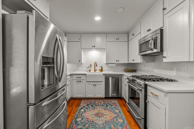 5412 S Grandview St, Little Rock, AR 72207 - kitchen featuring stainless steel appliances, a sink, wood finished floors, white cabinets, and recessed lighting