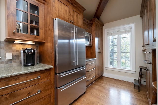5313 N Grandview St, Little Rock, AR 72207 - kitchen featuring stainless steel appliances, brown cabinets, beamed ceiling, glass insert cabinets, and tasteful backsplash