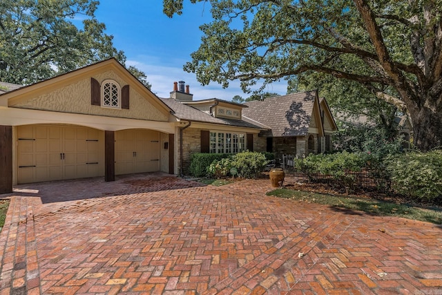 5313 N Grandview St, Little Rock, AR 72207 - view of front of home with stone siding, a garage, decorative driveway, and a chimney