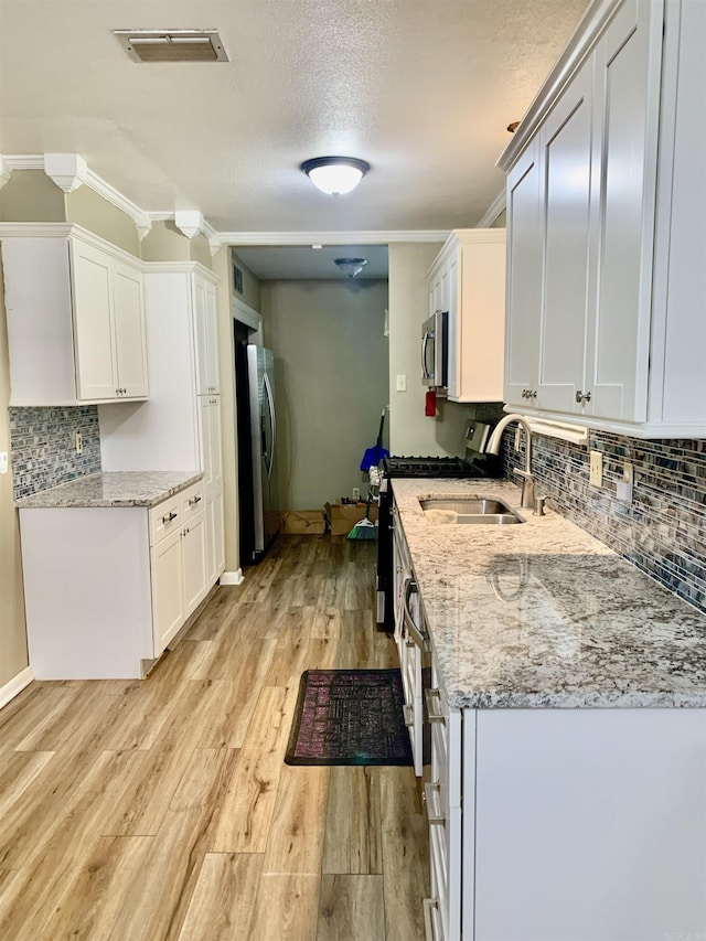5405 Dreher Ln, Little Rock, AR 72209 - kitchen with appliances with stainless steel finishes, a textured ceiling, backsplash, light wood-style floors, and white cabinets