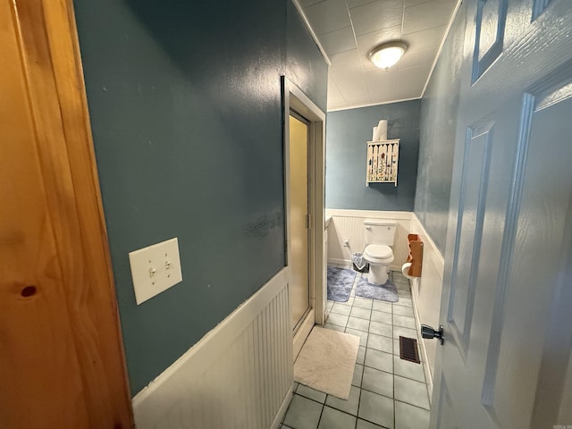 221 N Garfield Ave, Piggott, AR 72454 - bathroom featuring tile patterned floors, toilet, and a wainscoted wall