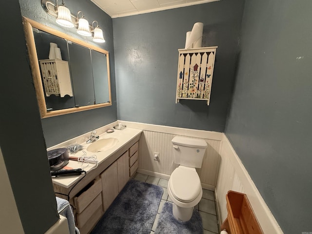221 N Garfield Ave, Piggott, AR 72454 - bathroom with toilet, vanity, tile patterned floors, and a wainscoted wall