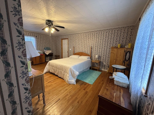 221 N Garfield Ave, Piggott, AR 72454 - bedroom with wallpapered walls, light wood-style floors, a ceiling fan, and ornamental molding