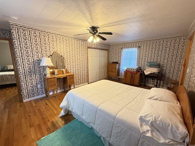 221 N Garfield Ave, Piggott, AR 72454 - bedroom with wood finished floors, wallpapered walls, a ceiling fan, baseboards, and ornamental molding