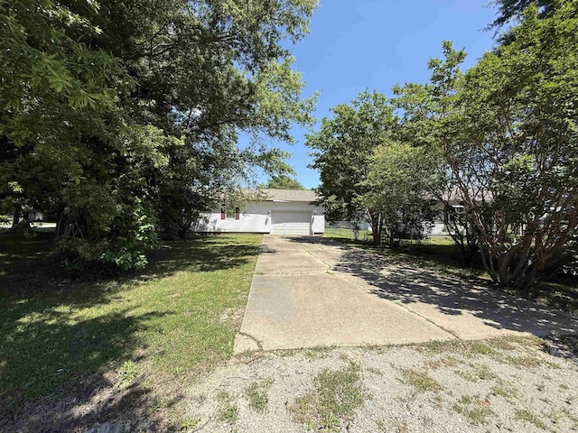 221 N Garfield Ave, Piggott, AR 72454 - obstructed view of property featuring an attached garage, concrete driveway, and a front lawn