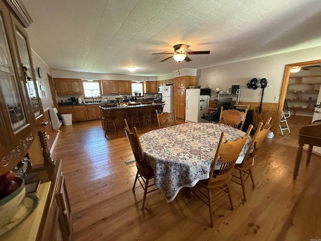221 N Garfield Ave, Piggott, AR 72454 - dining room featuring wood-type flooring, a ceiling fan, a wainscoted wall, and wood walls