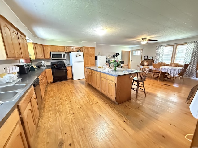 221 N Garfield Ave, Piggott, AR 72454 - kitchen featuring stainless steel appliances, dark countertops, a center island, light wood-style floors, and a breakfast bar