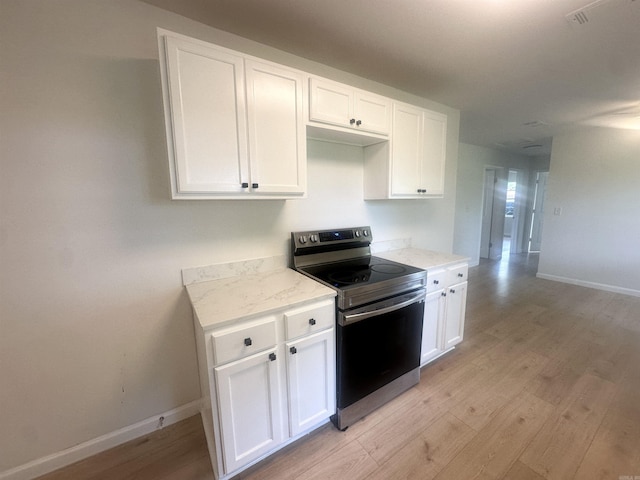 3003 Hollywood St, Texarkana, TX 75503 - kitchen with stainless steel electric range oven, light wood-style floors, white cabinets, and baseboards