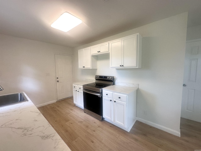 3003 Hollywood St, Texarkana, TX 75503 - kitchen featuring stainless steel electric stove, light wood-style flooring, baseboards, a sink, and white cabinets