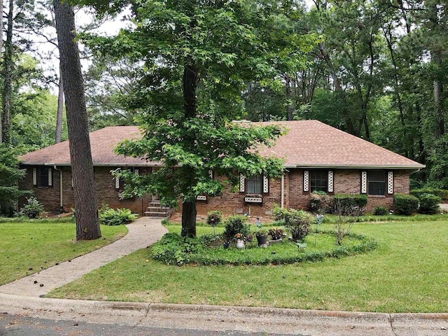 view of front of property with a front lawn, brick siding, and roof with shingles