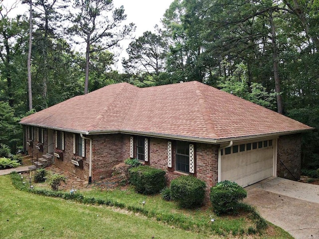 view of front of home featuring an attached garage, roof with shingles, driveway, and brick siding