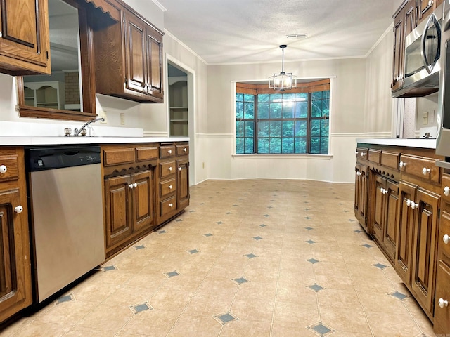 kitchen featuring stainless steel appliances, ornamental molding, a wainscoted wall, light countertops, and a chandelier