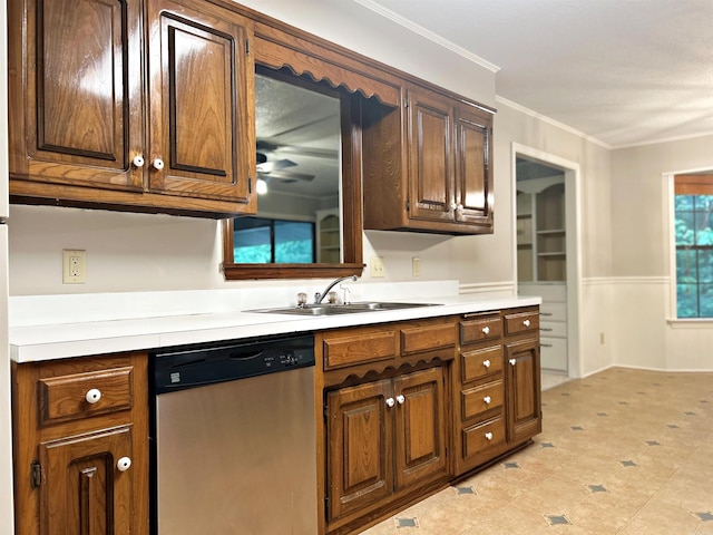 kitchen with dishwasher, a sink, light countertops, crown molding, and wainscoting