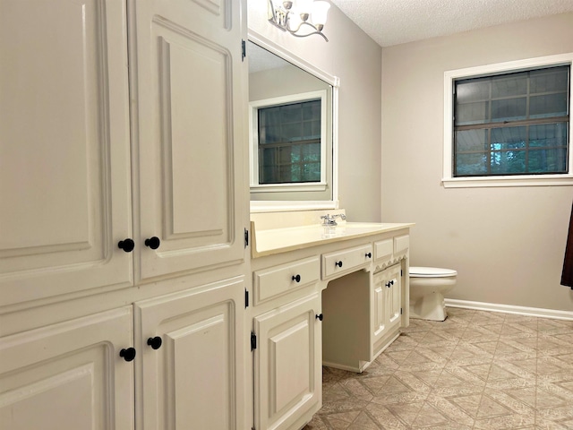 bathroom featuring vanity, toilet, baseboards, a textured ceiling, and tile patterned floors