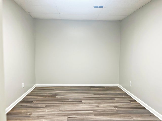 unfurnished room with wood finished floors, baseboards, and a paneled ceiling