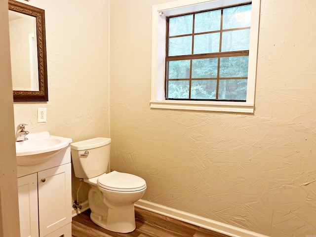 bathroom with wood finished floors, vanity, baseboards, and toilet
