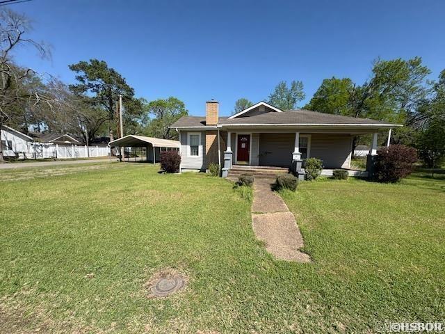 405 3rd Ave, Murfreesboro, AR 71958 - view of front of house featuring a porch, a detached carport, a front lawn, and a chimney