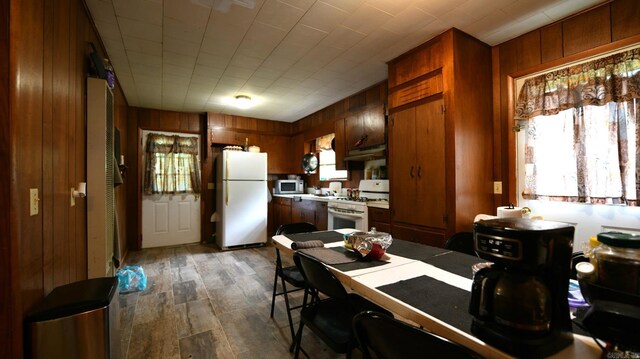911 Gillham, Mena, AR 71953 - kitchen featuring white appliances, wood walls, light countertops, under cabinet range hood, and brown cabinetry