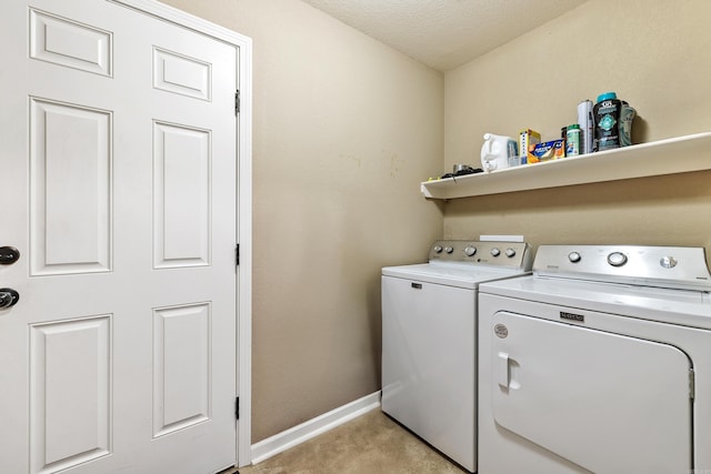 laundry room featuring washer and clothes dryer, baseboards, a textured ceiling, and light carpet
