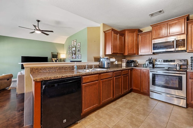 kitchen with appliances with stainless steel finishes, a sink, a peninsula, brown cabinets, and ceiling fan