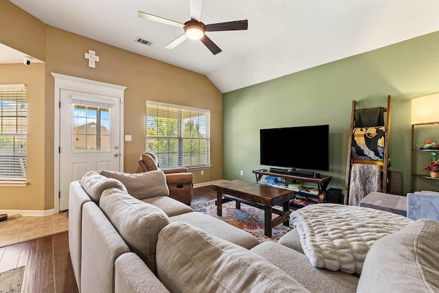 living area featuring a ceiling fan, wood finished floors, healthy amount of natural light, vaulted ceiling, and baseboards