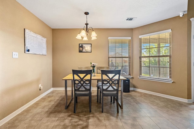 tiled dining space with a chandelier and baseboards