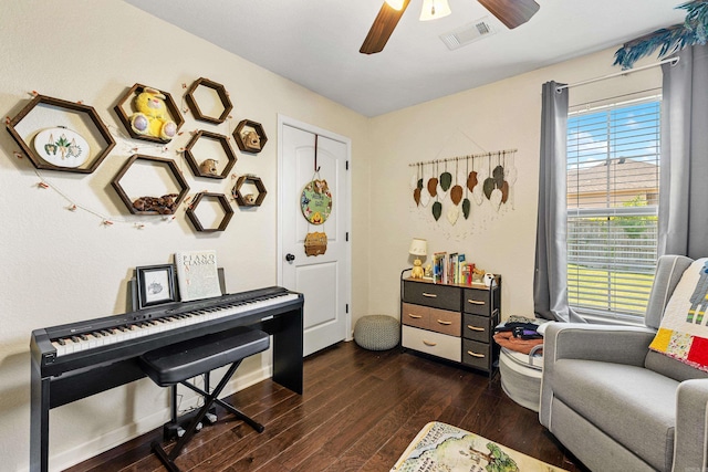 living area featuring dark wood-type flooring, a ceiling fan, and healthy amount of natural light