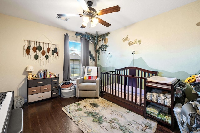 bedroom featuring wood finished floors, a nursery area, and a ceiling fan
