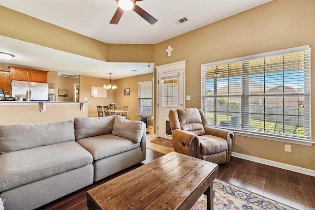 living room with a chandelier, a ceiling fan, dark wood-style flooring, and baseboards