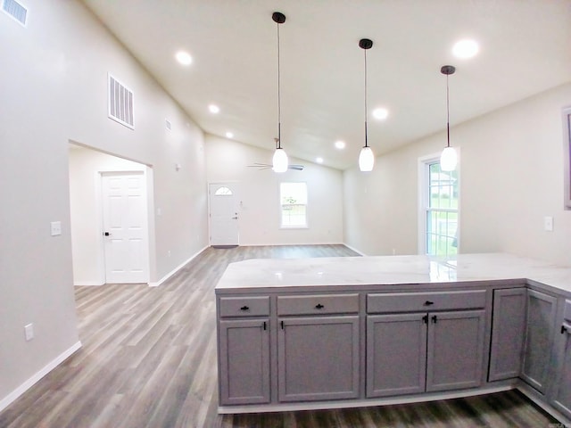 kitchen with gray cabinets, a peninsula, healthy amount of natural light, wood finished floors, and lofted ceiling