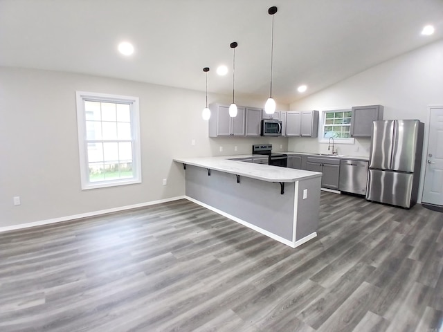 kitchen with appliances with stainless steel finishes, gray cabinets, a sink, a peninsula, and light countertops