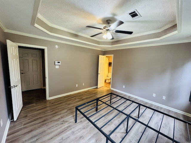 112 Seminole Cir, Austin, AR 72023 - unfurnished bedroom with a raised ceiling, wood finished floors, a textured ceiling, crown molding, and baseboards