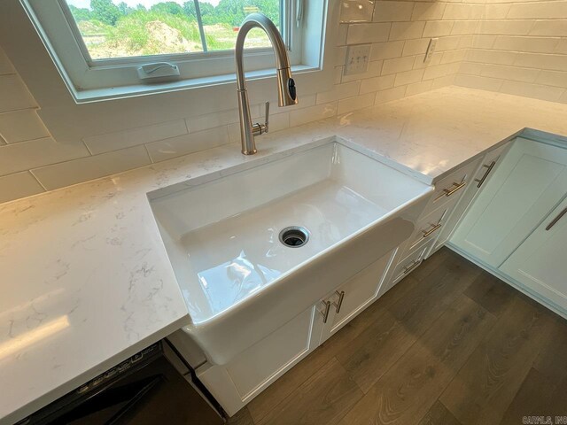111 Legacy Way, Ward, AR 72176 - detailed view of a sink, dark wood-type flooring, white cabinetry, light stone countertops, and backsplash